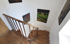 Eine Holztreppe mit Handlauf, weißen Wänden und drei gerahmten Bildern.