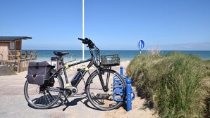 Ein Fahrrad am Strand, in der Nähe eines Rettungsturms und einem Schild, das einen kinderfreundlichen Bereich kennzeichnet.