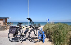 Ein Fahrrad am Strand, in der Nähe eines Rettungsturms und einem Schild, das einen kinderfreundlichen Bereich kennzeichnet.