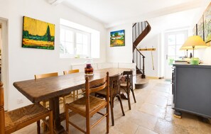 Un espace repas comprenant une table en bois, des chaises et des œuvres d’art accrochées aux murs.