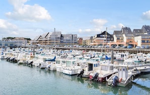 Un port de plaisance où de nombreux bateaux sont amarrés, entouré d’immeubles d’habitation.