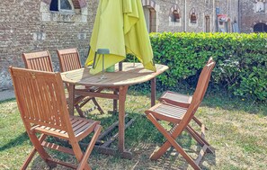 A round wooden table with a yellow umbrella, accompanied by two wooden chairs. - Au c?ur des sites du D-Day (Géfosse-Fontenay)