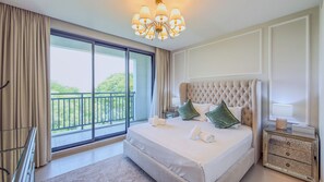 Ein Hotelzimmer mit einem großen Bett, einer Kristallleuchter, einem Nachttisch und Blick auf Grünfläche.