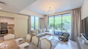 A modern living room with a dining area, large windows, and a kitchen. - Maple Residences - Dubai Hills Estate (Dubai)