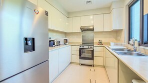 Een moderne keuken met een roestvrijstalen koelkast, een magnetron, een oven en een spoelbak.
