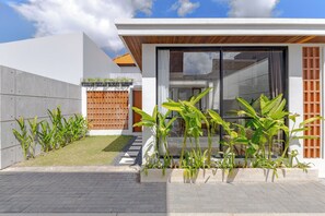 A modern house with a large glass door, a concrete wall, and a wooden fence. - Villa Kartal Bahce by Pertama Stay (Badung Regency)