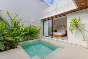 Ein modernes Schlafzimmer mit einem großen Bett, einer Glaswand und einem kleinen Pool.