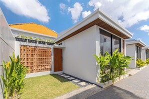 A modern house with a tiled roof, a wooden fence, and a paved driveway. - Villa Kartal Bahce by Pertama Stay (Badung Regency)