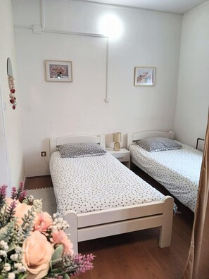 Ein Schlafzimmer mit zwei Einzelbetten, einem Nachttisch mit Lampe und einer Wandleuchte.