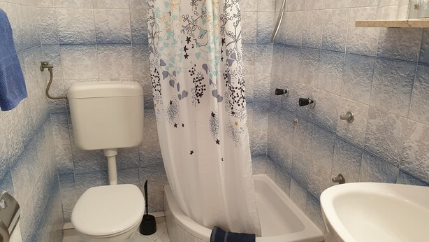 A bathroom with a toilet, a shower with a floral curtain, and a bathtub. - Villa Malfi-studio Apartment With Balcony and Sea View (Dubrovnik)