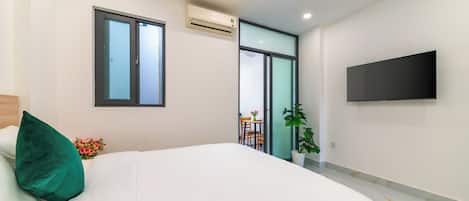 A modern bedroom with a bed, a flat-screen TV, and a window.
