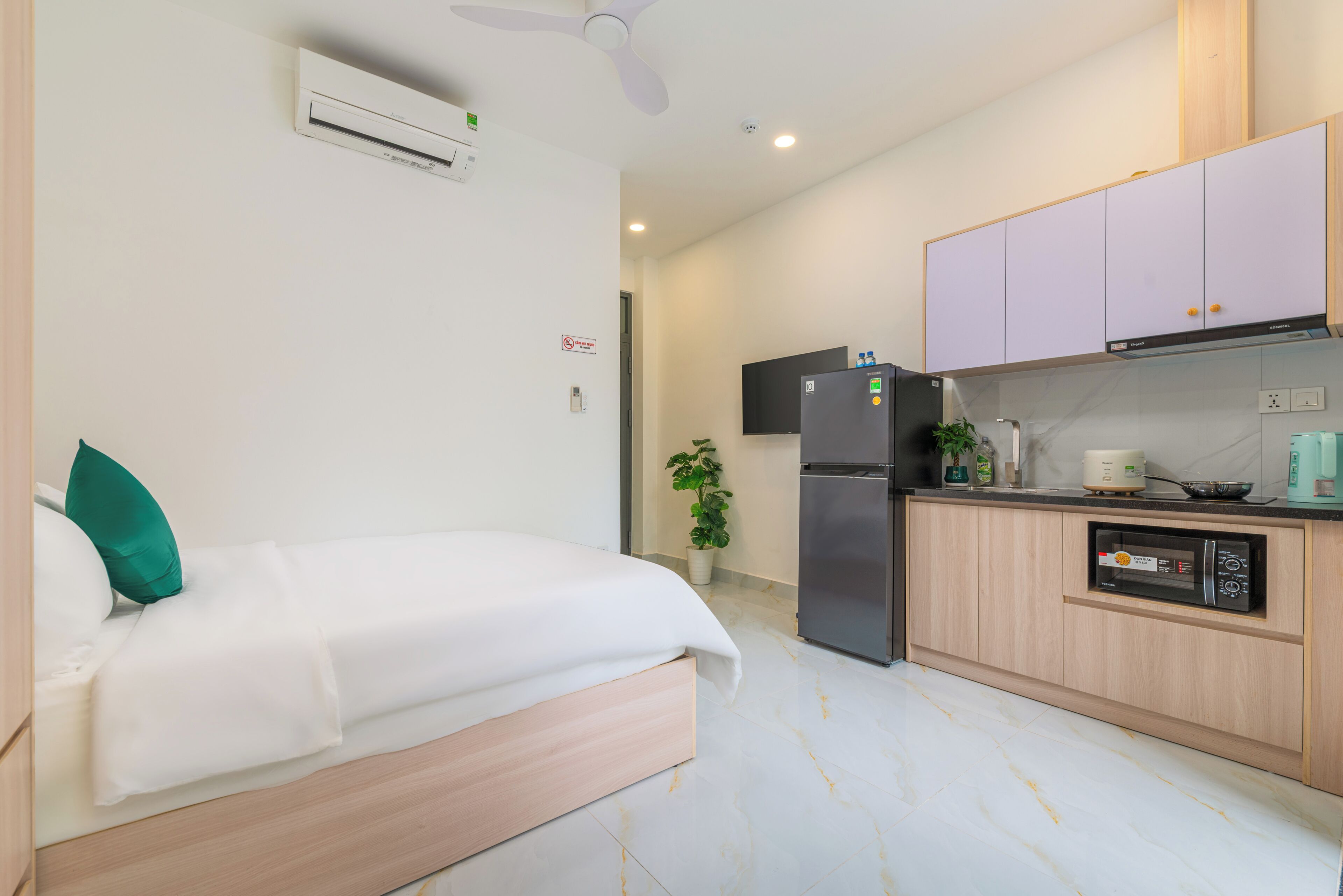 Une chambre d’hôtel équipée d’un lit, d’une kitchenette, d’un réfrigérateur, d’un four à micro-ondes et d’un ventilateur de plafond.