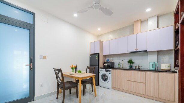 A modern kitchen with a dining area, including a washing machine, microwave, and various appliances. - LINH KHANG 2 APARTMENT DA NANG (Da Nang)