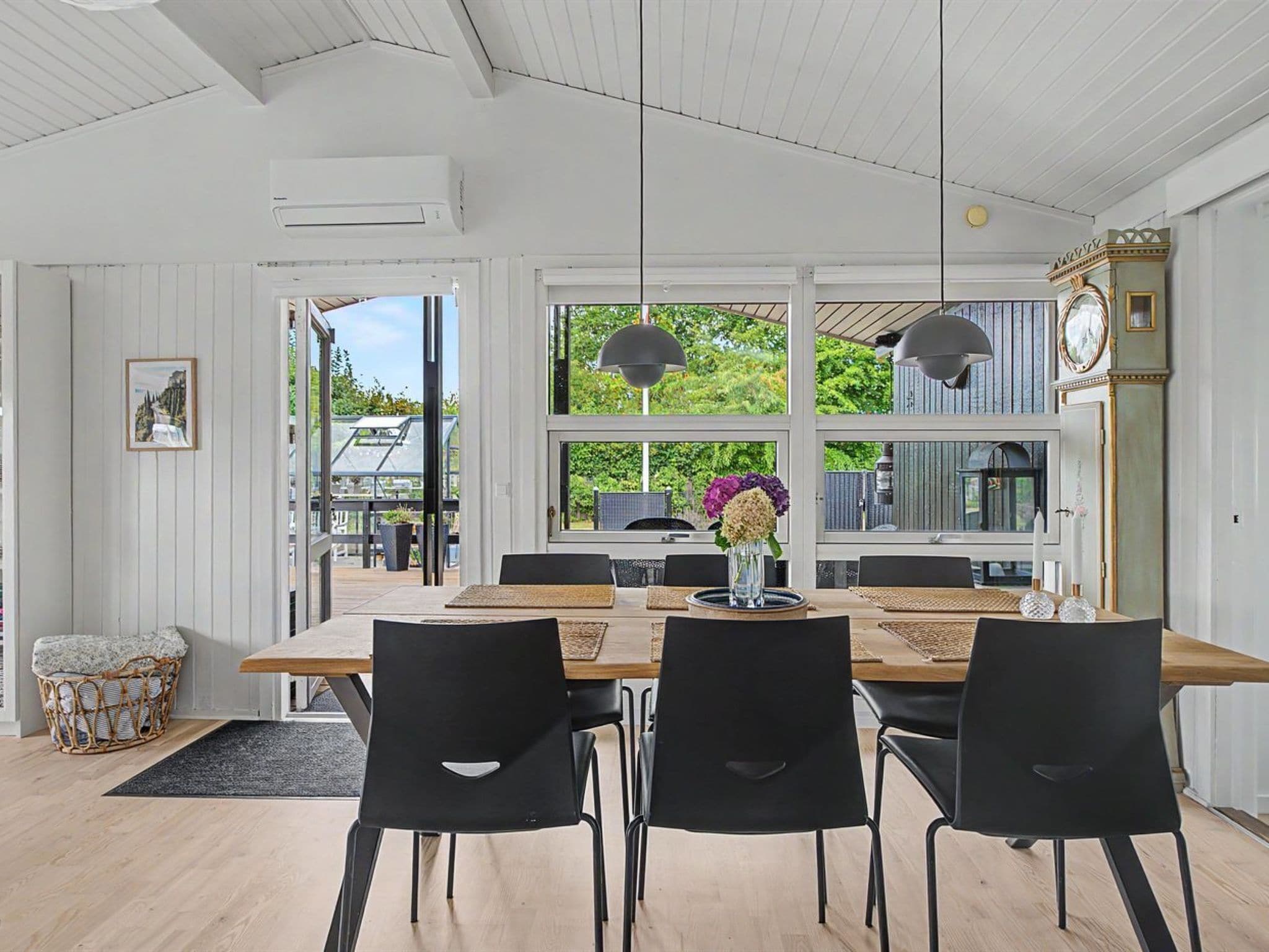 A dining area with a wooden table, black chairs, and pendant lights.