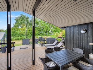 Eine Terrasse im Freien mit Holzdeck, einem Tisch mit Stühlen und einem Grill.