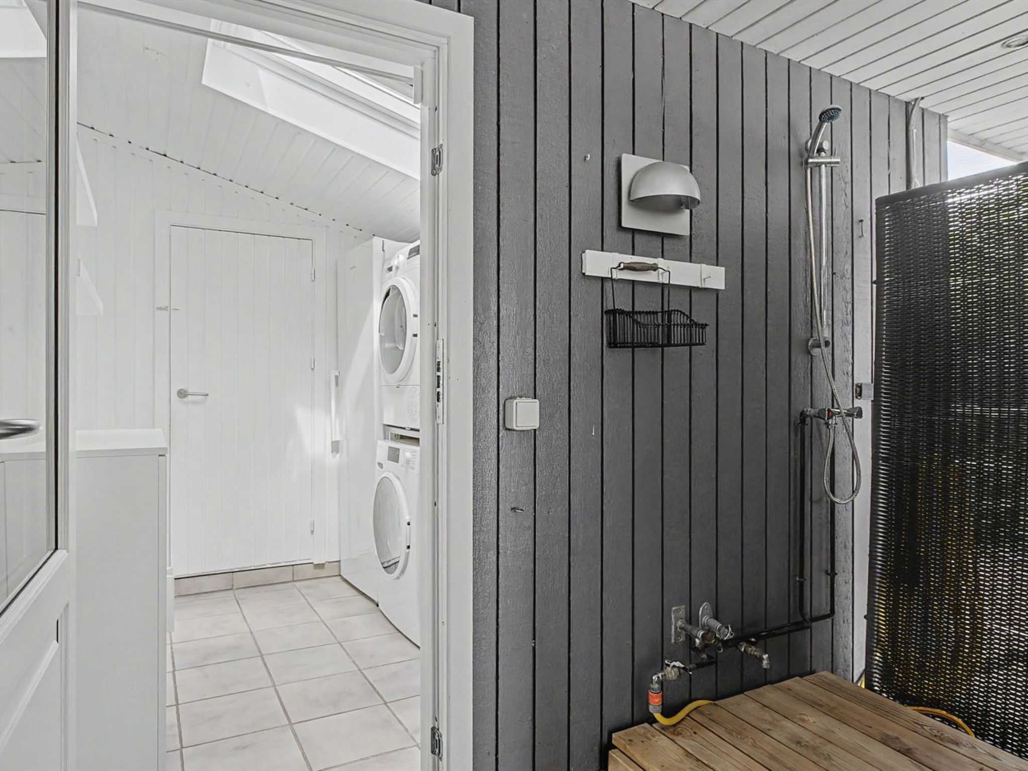 A bathroom with a washing machine, a shower, and a toilet.