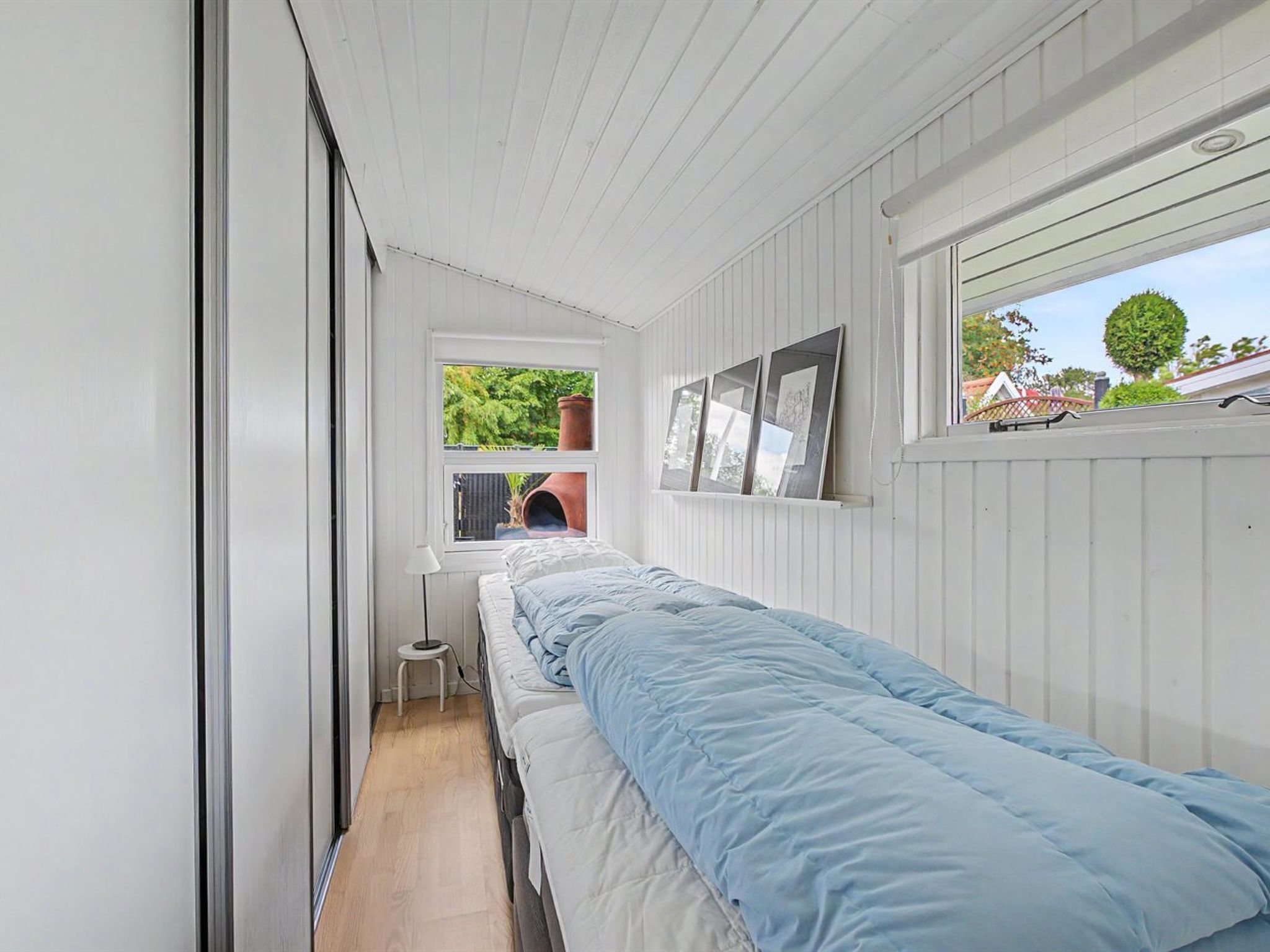 A narrow room with a bed, a window, and a door.