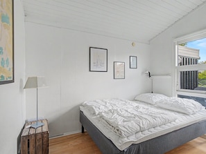 Ein Schlafzimmer mit einem Bett, einer Lampe und gerahmten Bildern an der Wand.