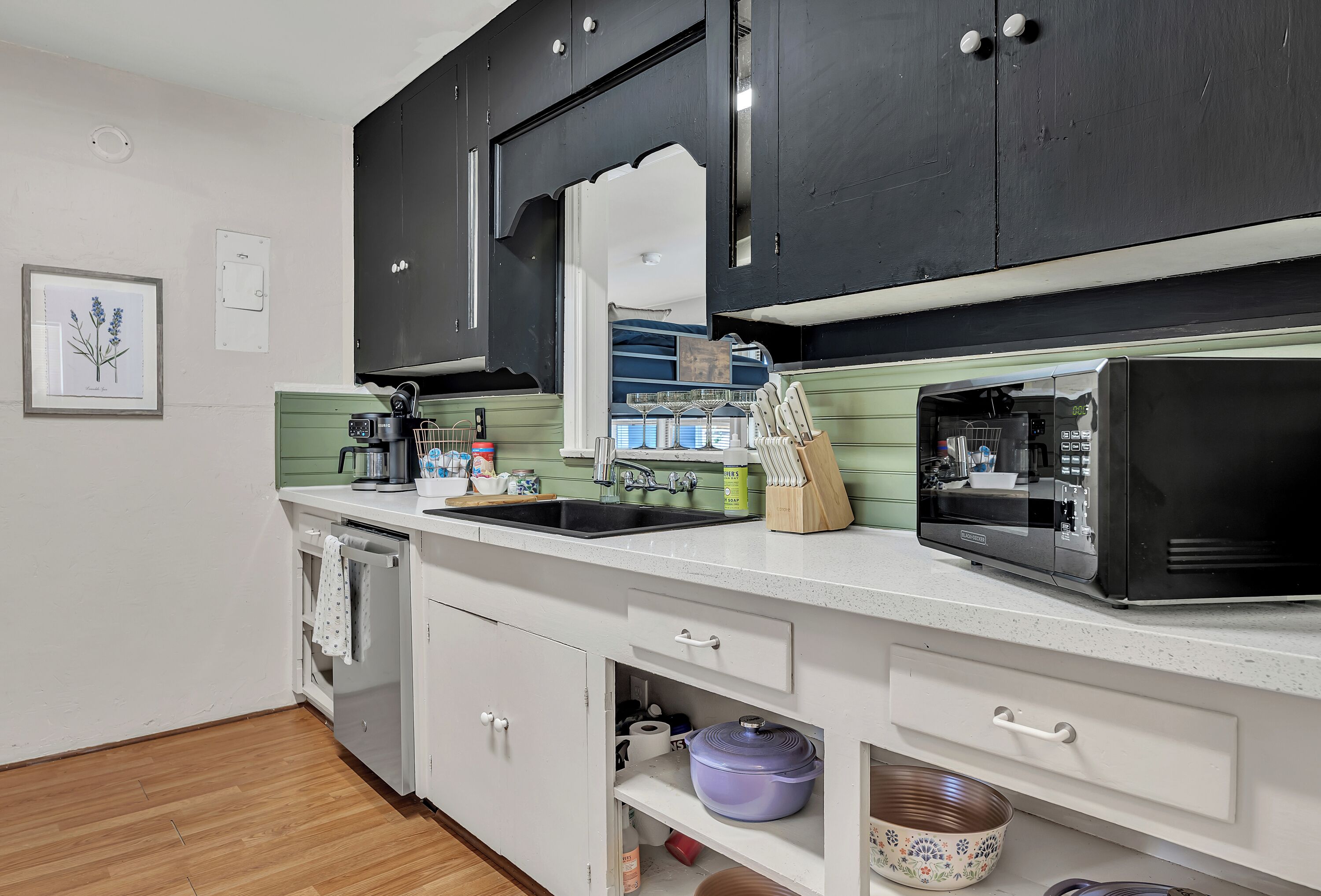 A kitchen with a microwave, sink, and cabinets.