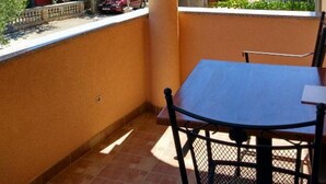 Ein Balkon mit Tisch und Stühlen, mit Blick auf ein Wohngebiet mit Häusern und Bäumen.