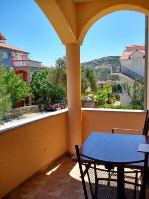 Ein Balkon mit Tisch und Stühlen, mit Blick auf ein Wohngebiet mit Häusern und Bäumen.