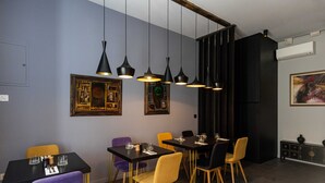 A dining area with a black table, yellow and purple chairs, and black pendant lights. - Rooms Lejletul - Double Room (Dubrovnik)