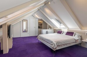 Ein Schlafzimmer mit schrägem Dach, einem Bett mit Kissen, einem Heizkörper und einem Spiegel.
