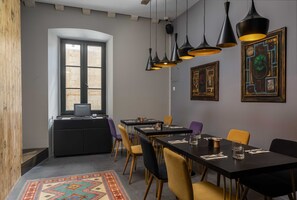 Ein Konferenzraum mit langem Tisch, Stühlen und Pendelleuchten.