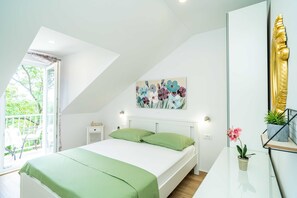 Ein Schlafzimmer mit einem Bett, einem Gemälde, einem Fenster und einer Pflanze.