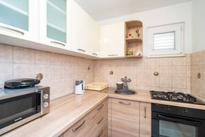 Eine moderne Küche mit Gasherd, Backofen, Mikrowelle und Kaffeemaschine.