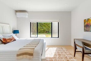 A bedroom with a bed, a desk, a window with a view of greenery, and a painting on the wall. - Soothing 2BR Private Suite, Porch and Parking, Fast WIFI; Near Bellevue downtown (Bellevue)