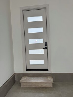 Eine Tür mit rechteckigem Fenster und einem kleinen Podest, das zum Eingang führt.