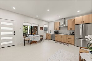 A modern kitchen with stainless steel appliances, wooden cabinets, and a dining area with a table and chairs. - Soothing 2BR Private Suite, Porch and Parking, Fast WIFI; Near Bellevue downtown (Bellevue)