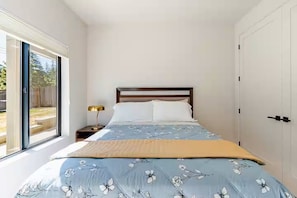 Ein Schlafzimmer mit einem Bett, einem Nachttisch, einer Lampe und einer Schiebetür zum Außenbereich.