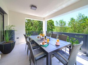 A balcony with a table set for two, outdoor seating, and a potted plant. - Wellness Villa- Four Bedroom Villa With Swimming Pool (Vinodol)