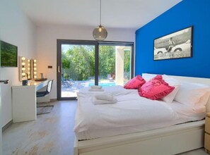 A bedroom with a bed, a vanity with lights, and a view of a pool. - Wellness Villa- Four Bedroom Villa With Swimming Pool (Vinodol)