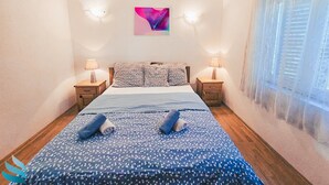 Ein Schlafzimmer mit einem Bett, zwei Nachttischen, einem Wandbild und einem Fenster mit Vorhängen.