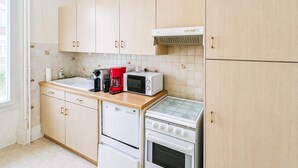 A kitchen with light wooden cabinets, a built-in microwave, a coffee maker, and a stove. - Amazing apartment in La Bourboule with WiFi (La Bourboule)