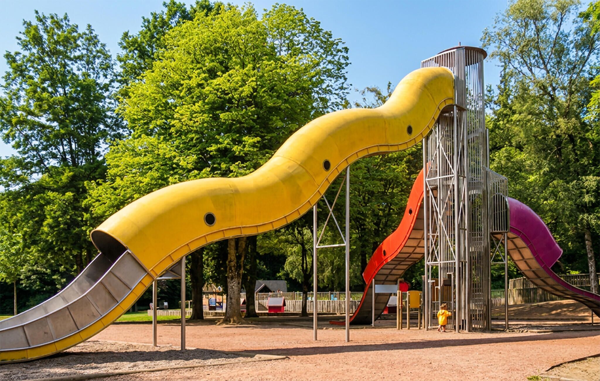 Un'area giochi con uno scivolo giallo, uno rosso e uno viola.