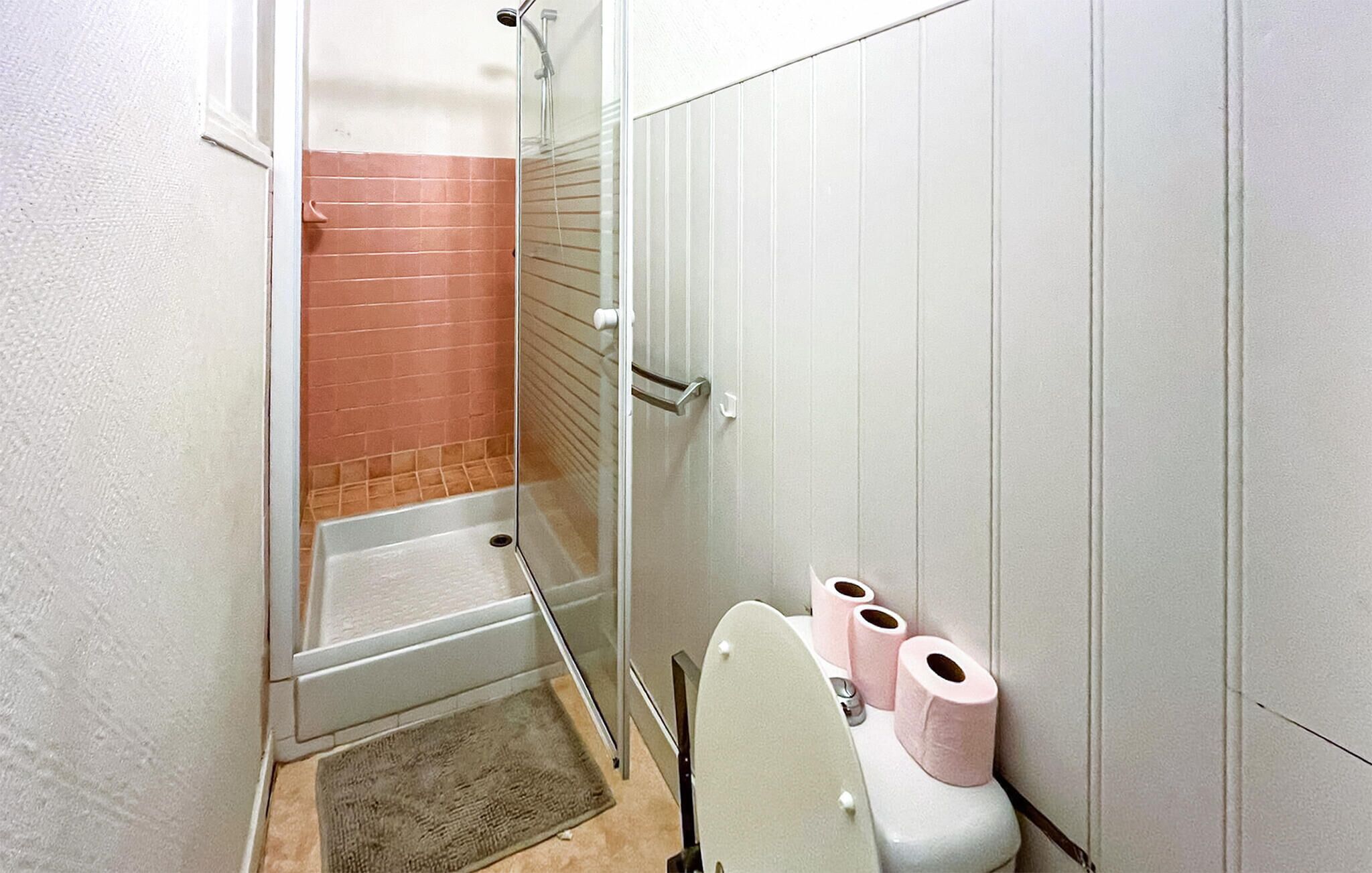 A bathroom with a shower, toilet, and a towel rack.