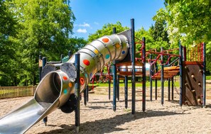 Ein Spielplatz mit Rutsche, Klettergerüsten und einem umzäunten Bereich.