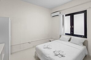 A hotel room with a bed, a nightstand, an air conditioning unit, and a window with curtains. - Casa Magnolia Apt 6 | Santurce Multifamily House (San Juan de Puerto Rico)