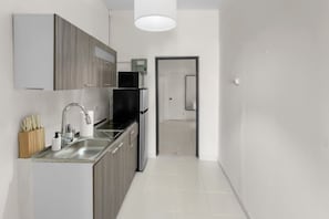 Eine moderne Küche mit Spüle aus Edelstahl, Holzschränken und einem schwarzen Kühlschrank.
