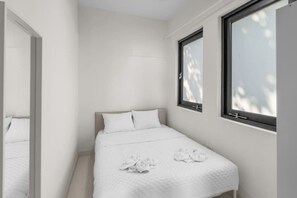 Ein schlichter Schlafzimmer mit einem Bett, einem großen Spiegel und zwei Fenstern.