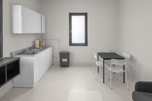 A modern kitchen with white cabinets, a black countertop, and a window above the sink. - Casa Magnolia Apt 7 | Santurce Multifamily House (San Juan de Puerto Rico)