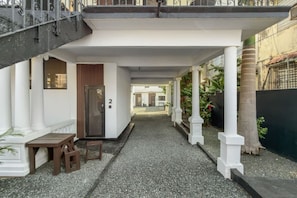 A covered outdoor corridor with a bench, a door marked with the number 2, and a gravel path. - Casa Magnolia Apt 2 | Santurce Multifamily House (San Juan de Puerto Rico)