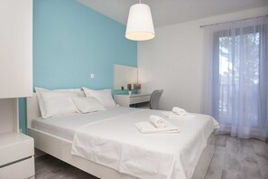 A modern bedroom with a bed, bedside tables, a desk, and a window with curtains. - Apartments Dva Galeba - Premium One Bedroom Apartment With Sea View (Bol)