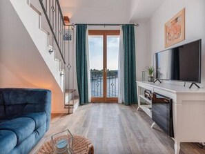 Ein modernes Wohnzimmer mit einem blauen Sofa, einem Flachbildfernseher und einem Balkon mit Blick.