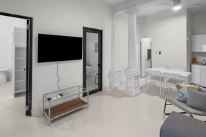 A modern living room with a flat-screen TV mounted on the wall, a glass coffee table, and a grey sofa. - Casa Magnolia Apt 1 | Santurce Multi Family House (San Juan de Puerto Rico)