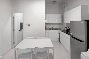 A modern kitchen with white cabinets, a stainless steel refrigerator, and a dining table with chairs. - Casa Magnolia Apt 1 | Santurce Multi Family House (San Juan de Puerto Rico)